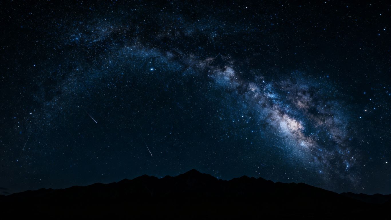 Starry night sky over mountains, Milky Way visible.