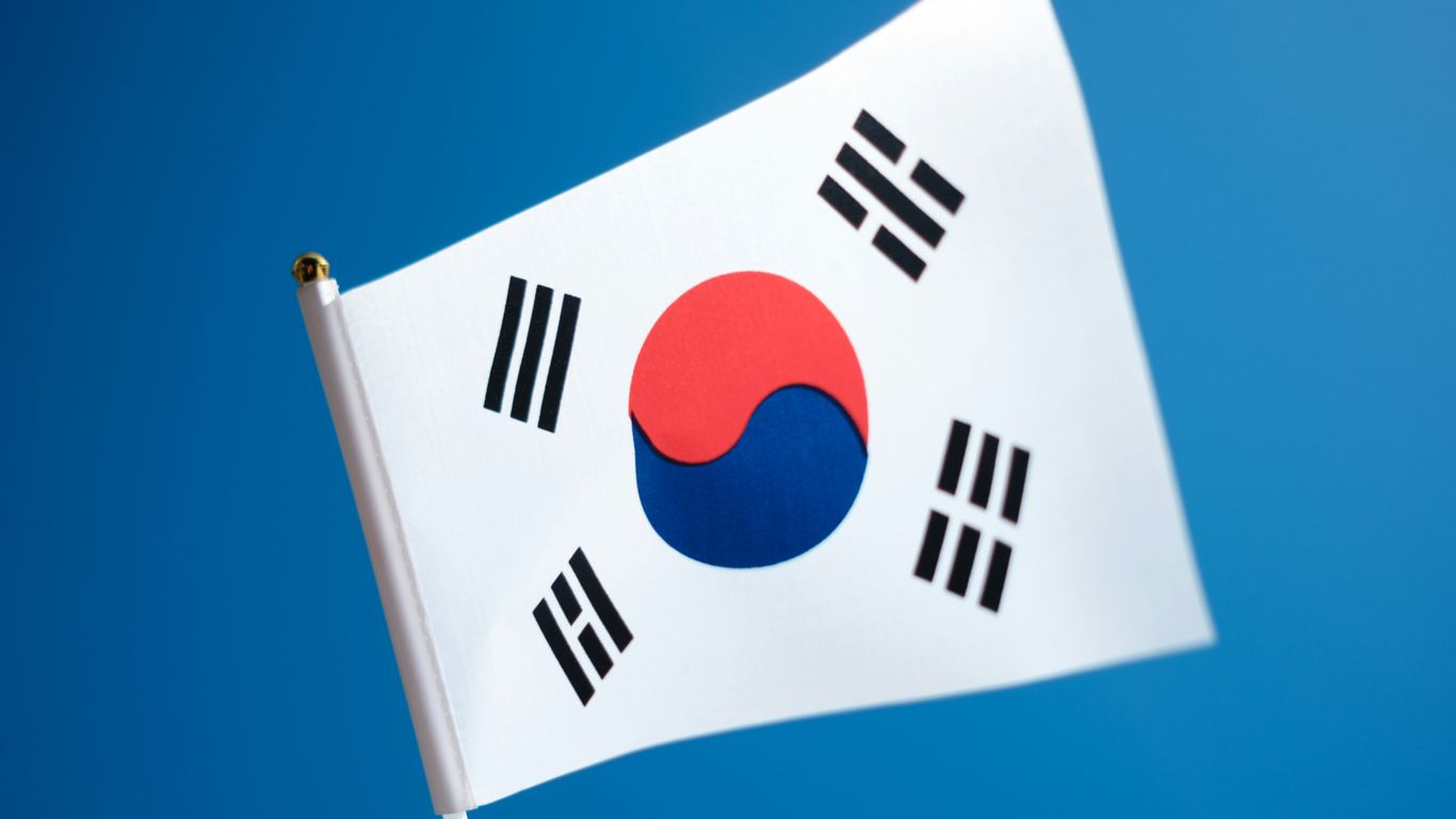 a korean flag flying in the wind with a blue sky in the background