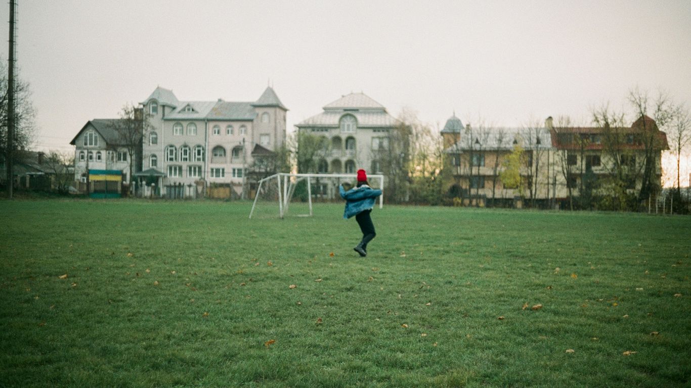 man in blue jacket and black pants walking on green grass field during daytime