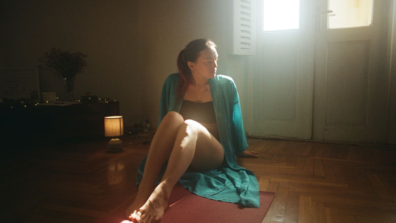 A woman sitting on a yoga mat in a room