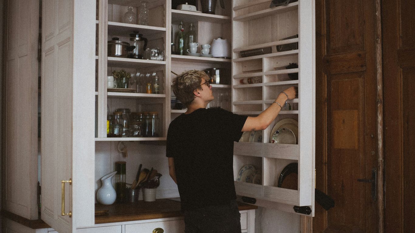 man standing near cabinet reaching plate