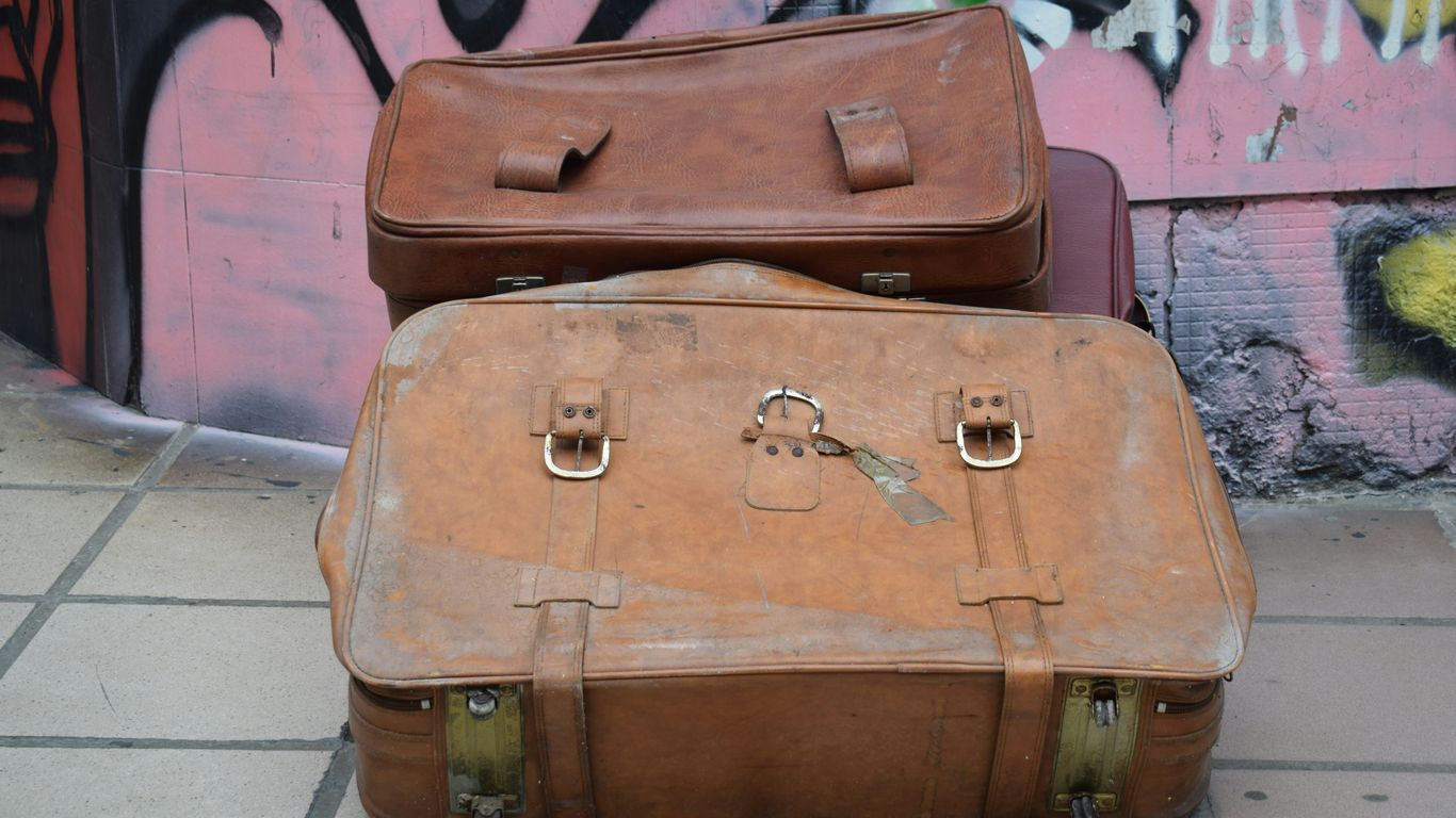 Two suitcases sitting on the ground in front of a wall with graffiti