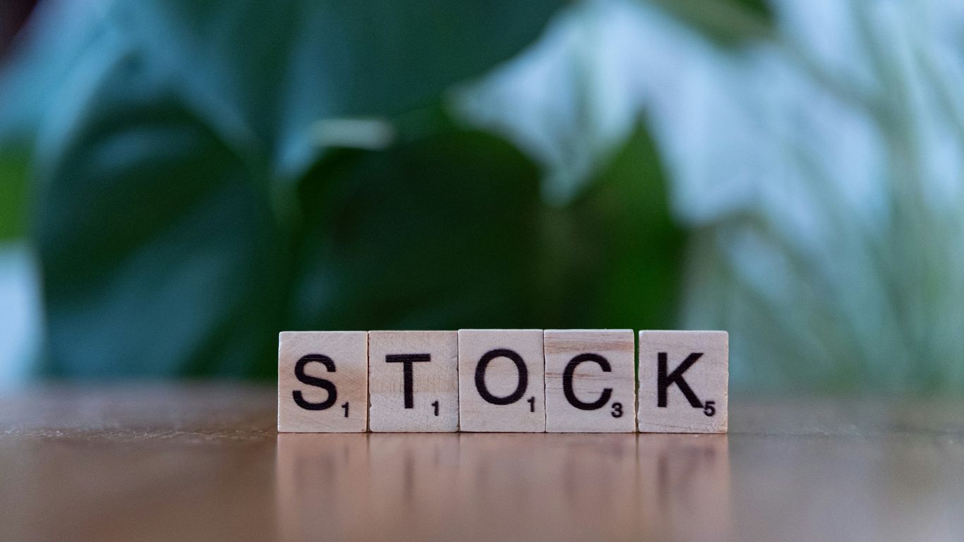 A wooden block spelling the word stock on a table
