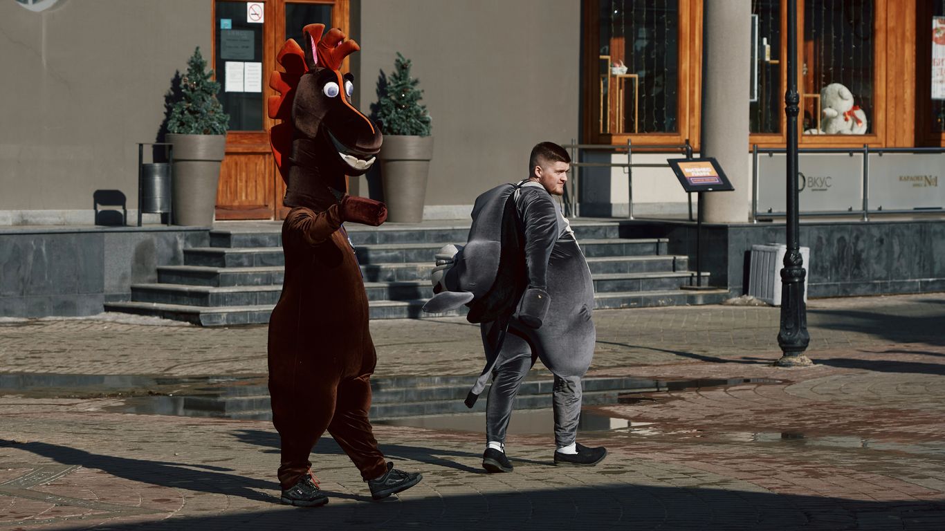 man in gray jacket and blue denim jeans standing beside brown horse statue