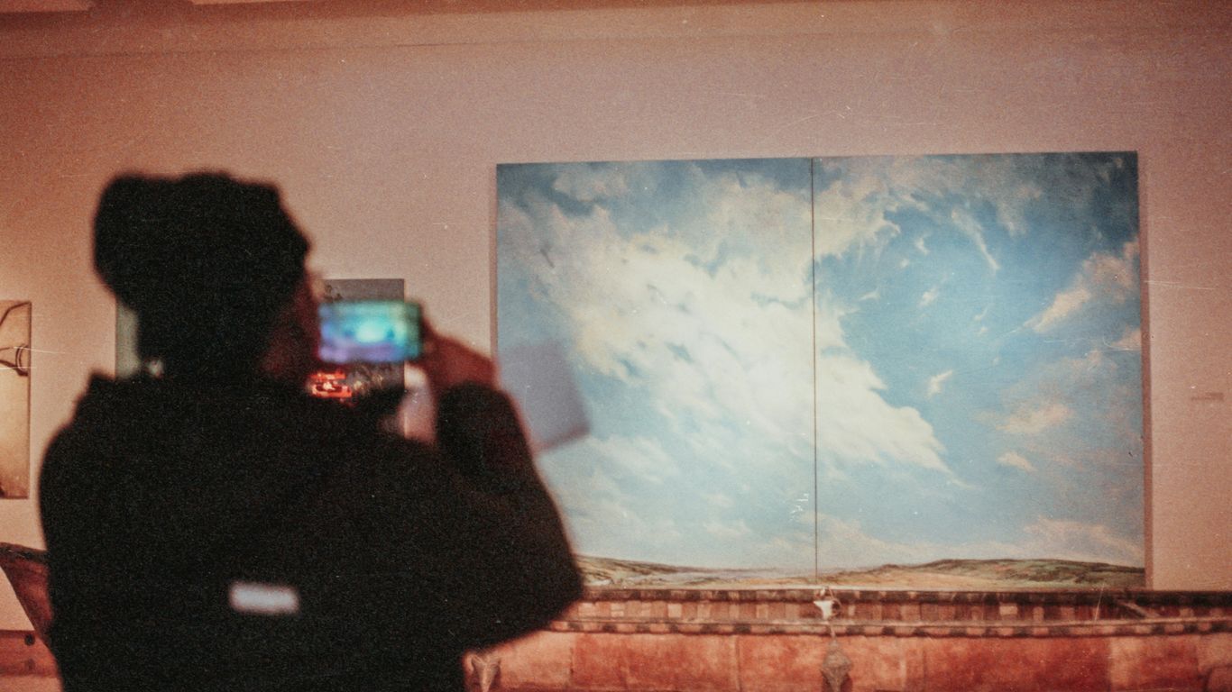 a person taking a picture of a painting on a wall