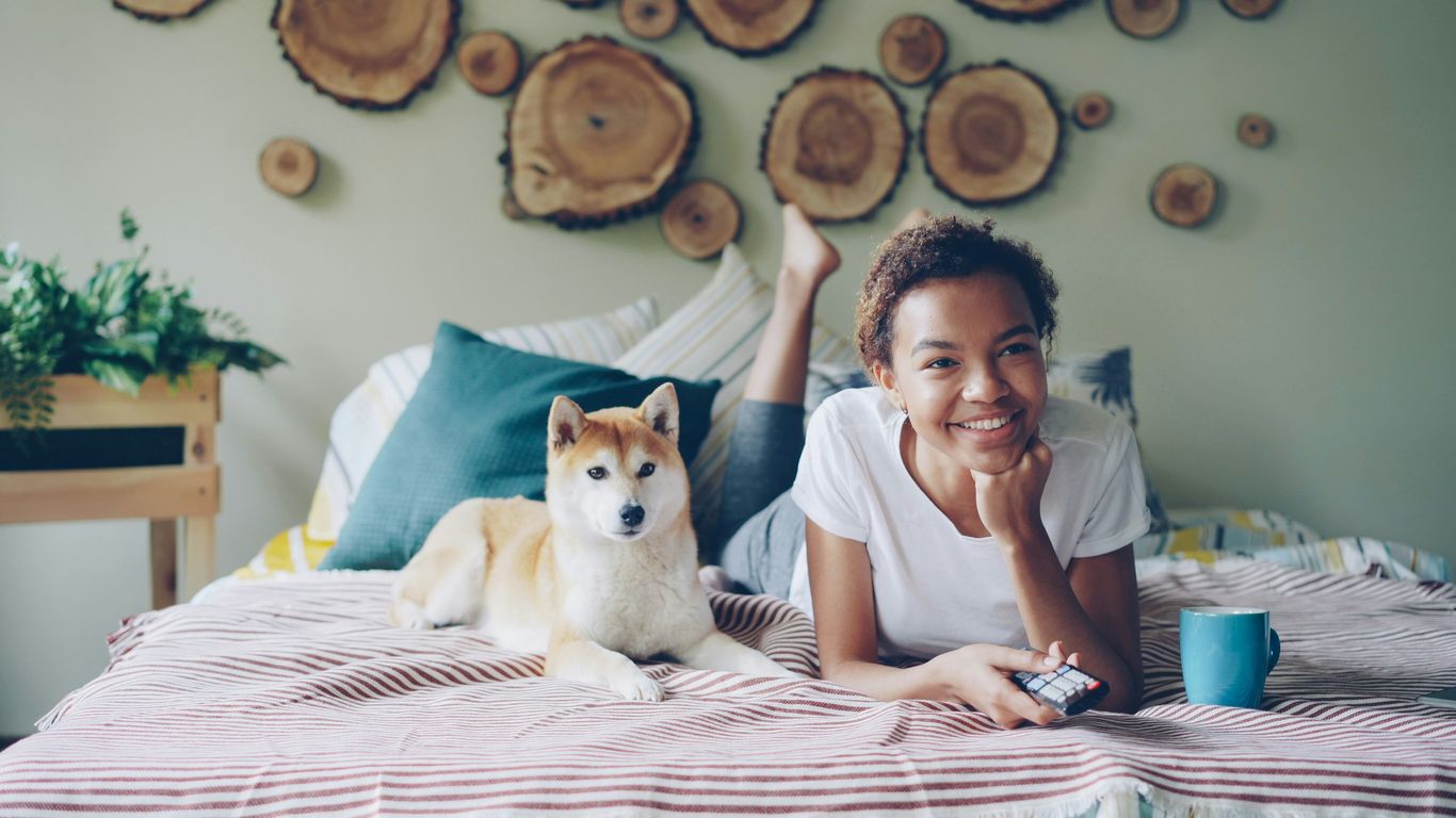 A woman and her dog relax on a bed.