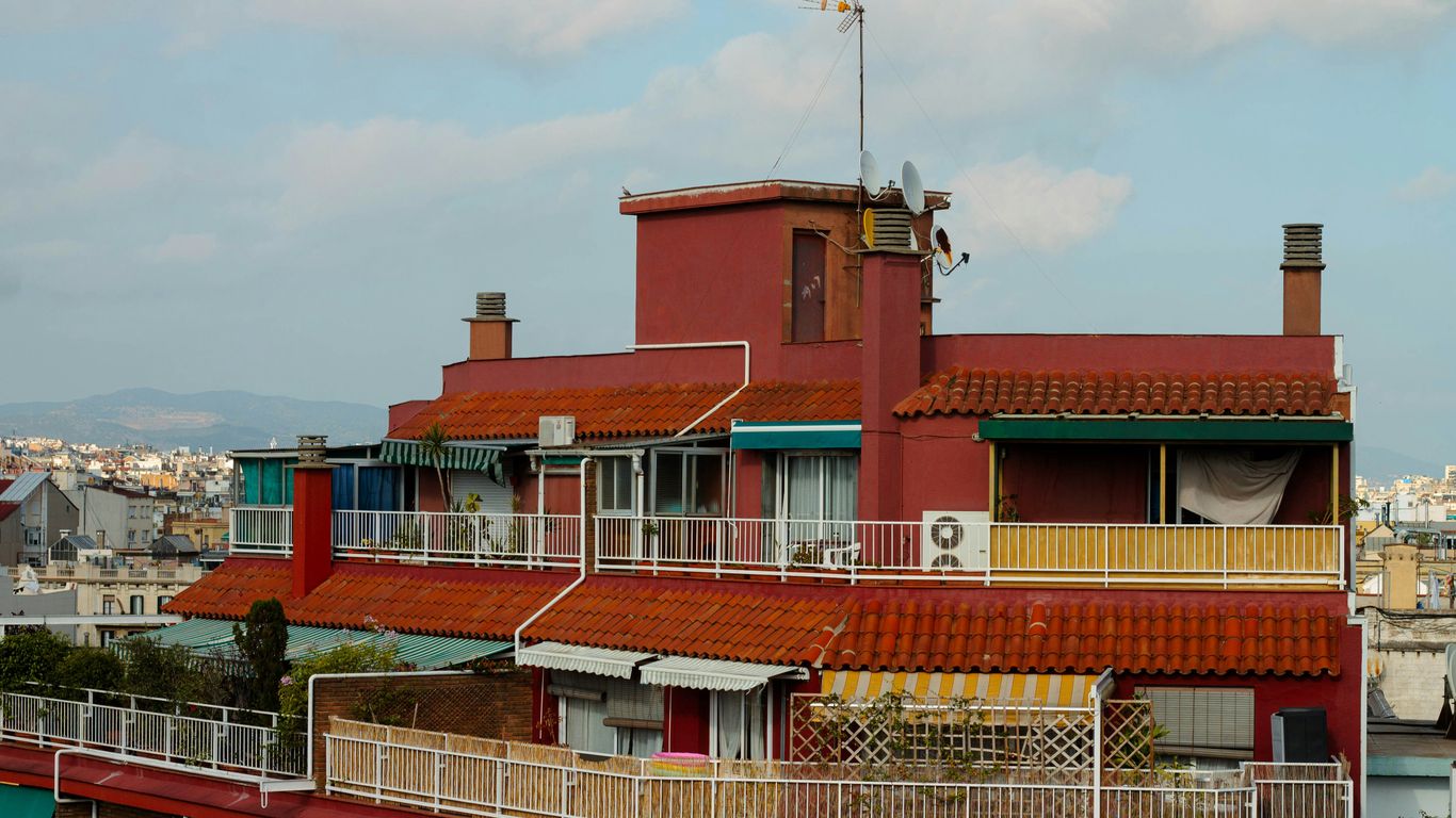 a tall red building with a balcony and a clock tower
