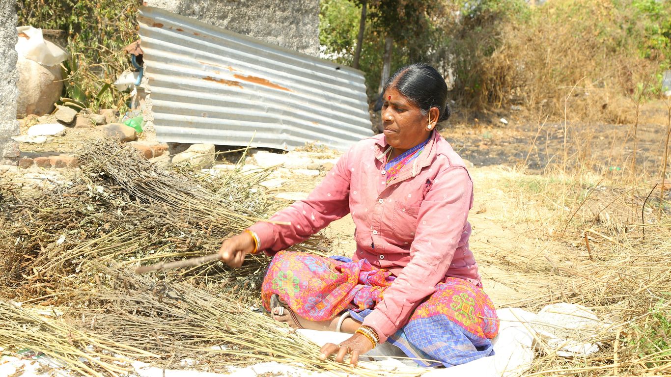 a woman sitting on the ground next to a pile of hay