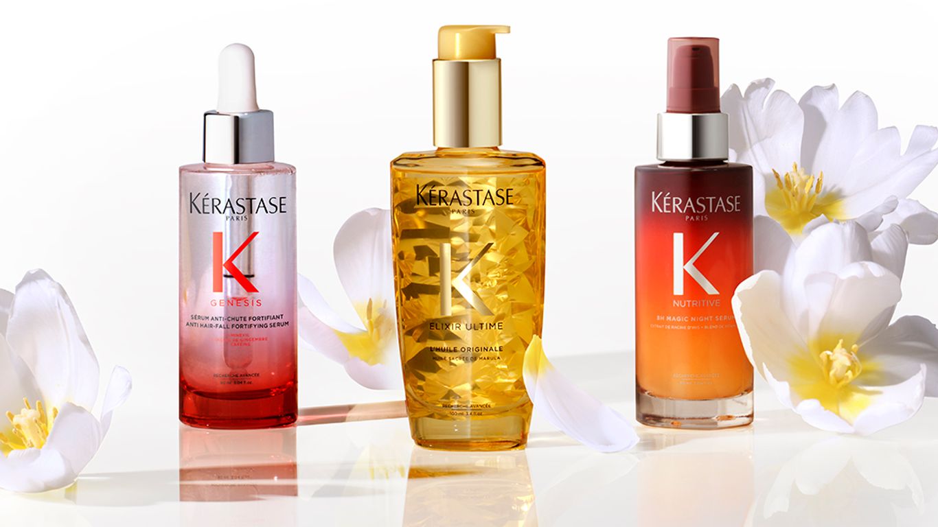 Three hair care bottles with white flowers on reflective surface.