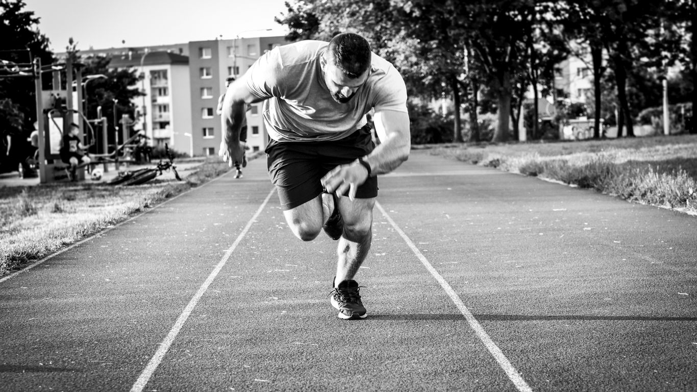 man in gray long sleeve shirt and black shorts running on road during daytime