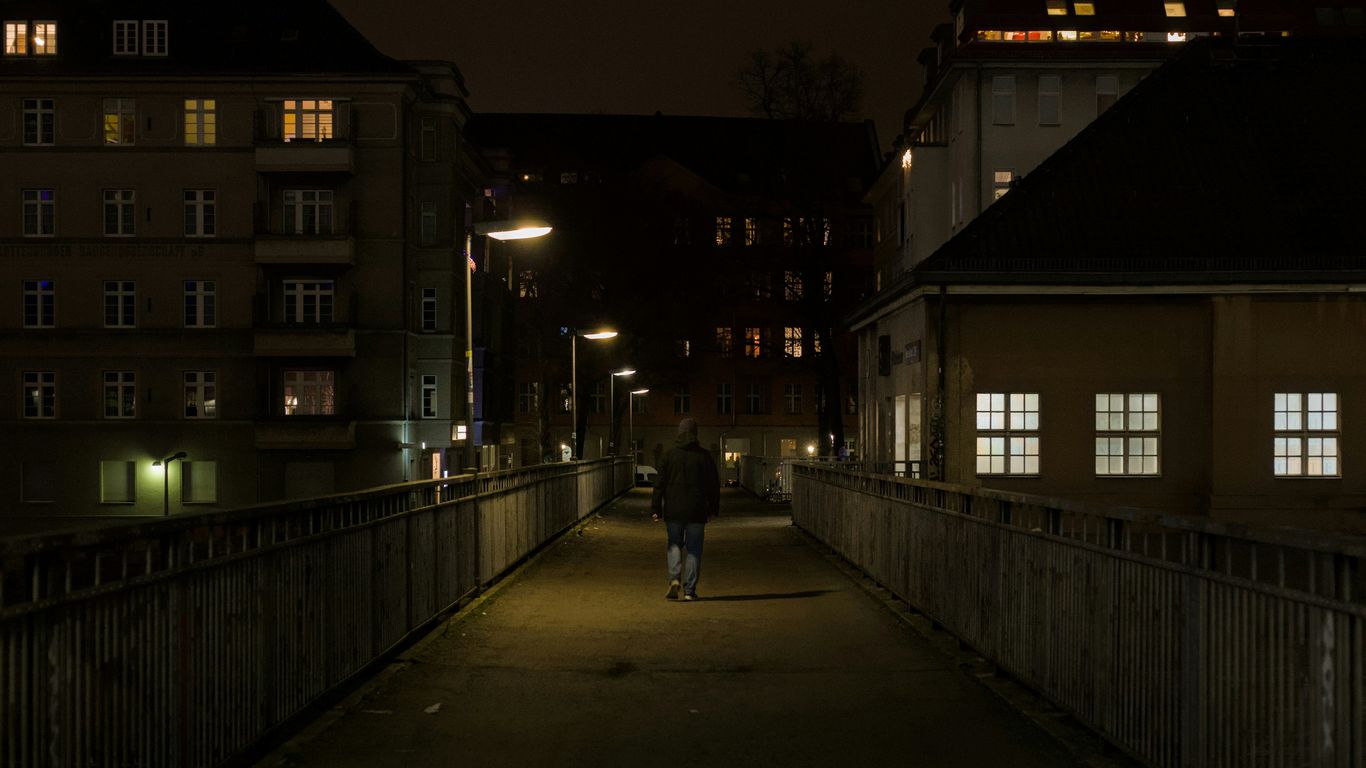 A lone person walks on a bridge at night.