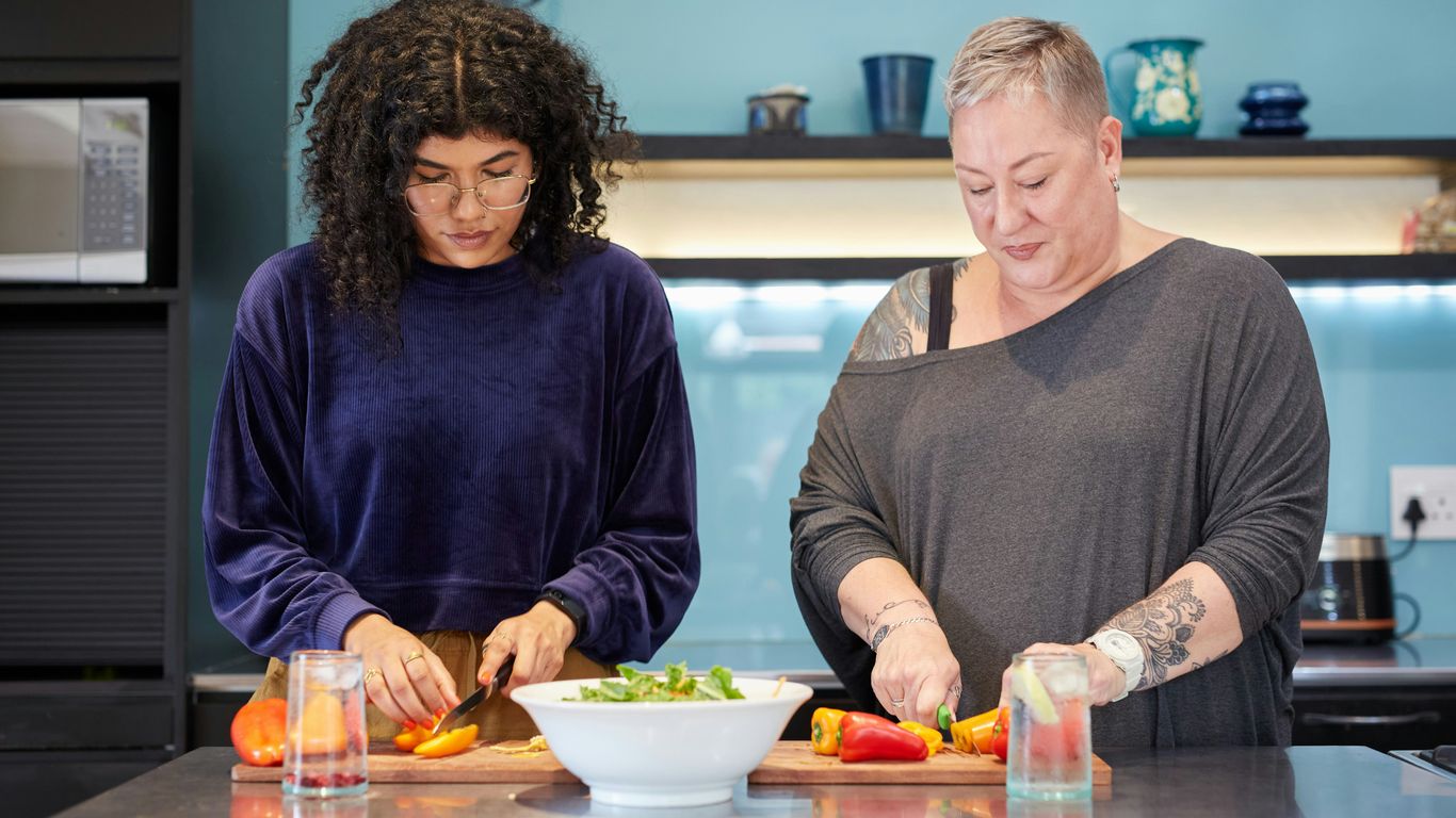a couple of women standing in a kitchen preparing food