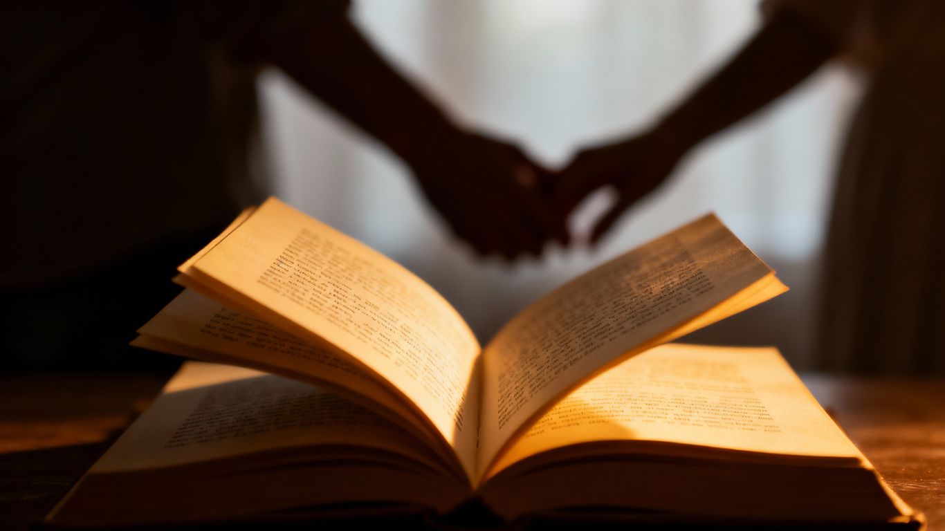 Open book with hands reaching, symbolizing love and connection.