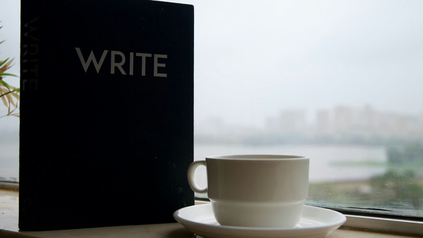 Notebook with the word write and coffee cup by window