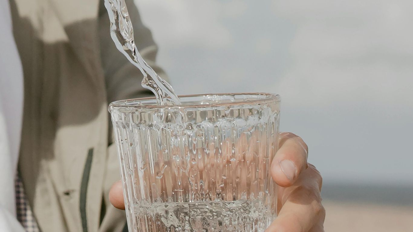 Water being poured into a glass held by a person.