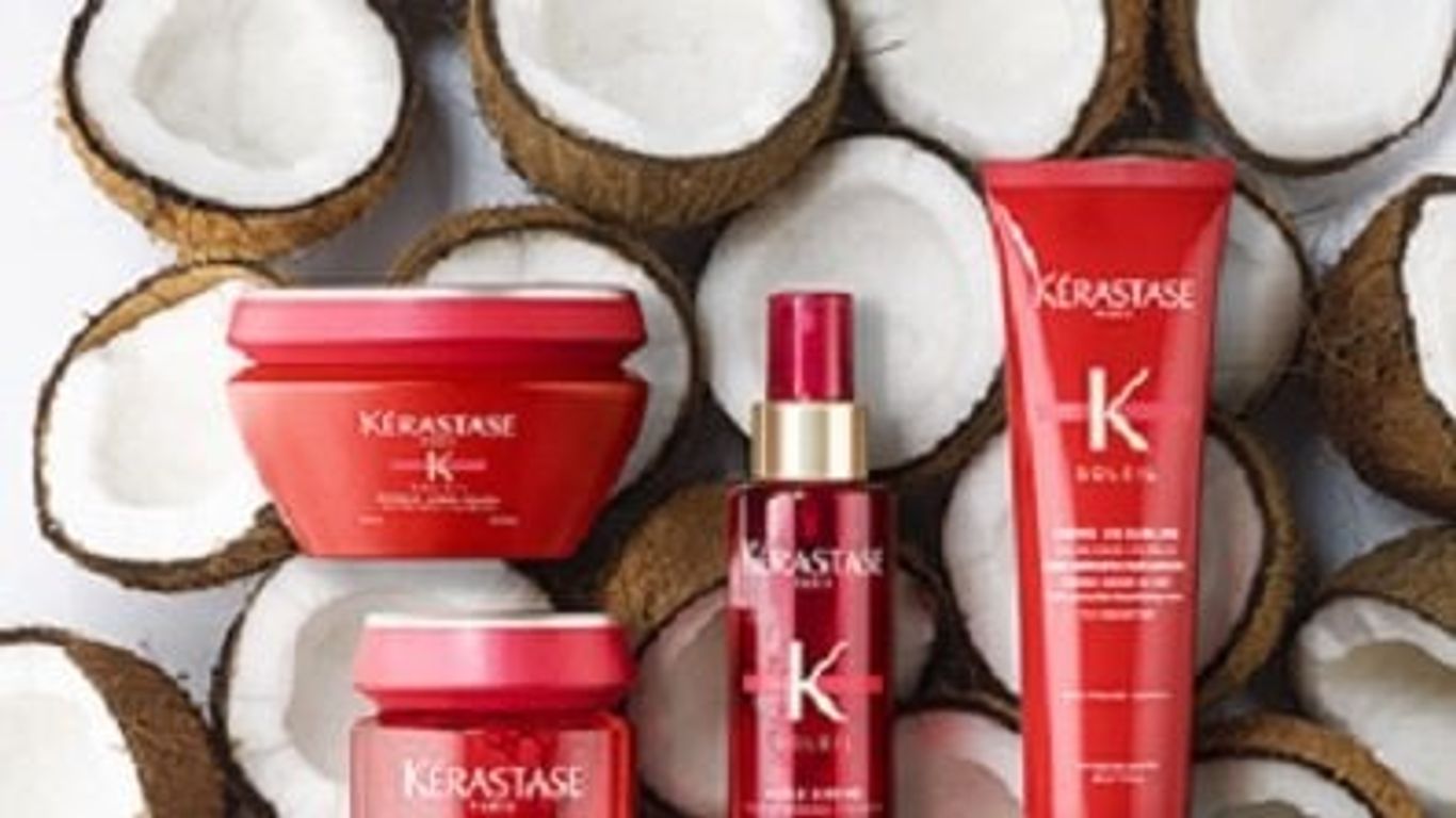 Haircare products displayed among halved coconuts on a white background.