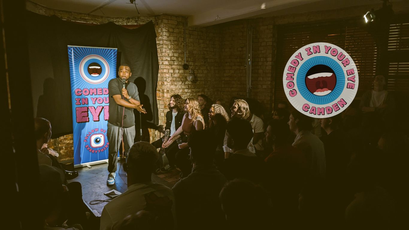 A comedian performs on stage to an audience at a comedy club.