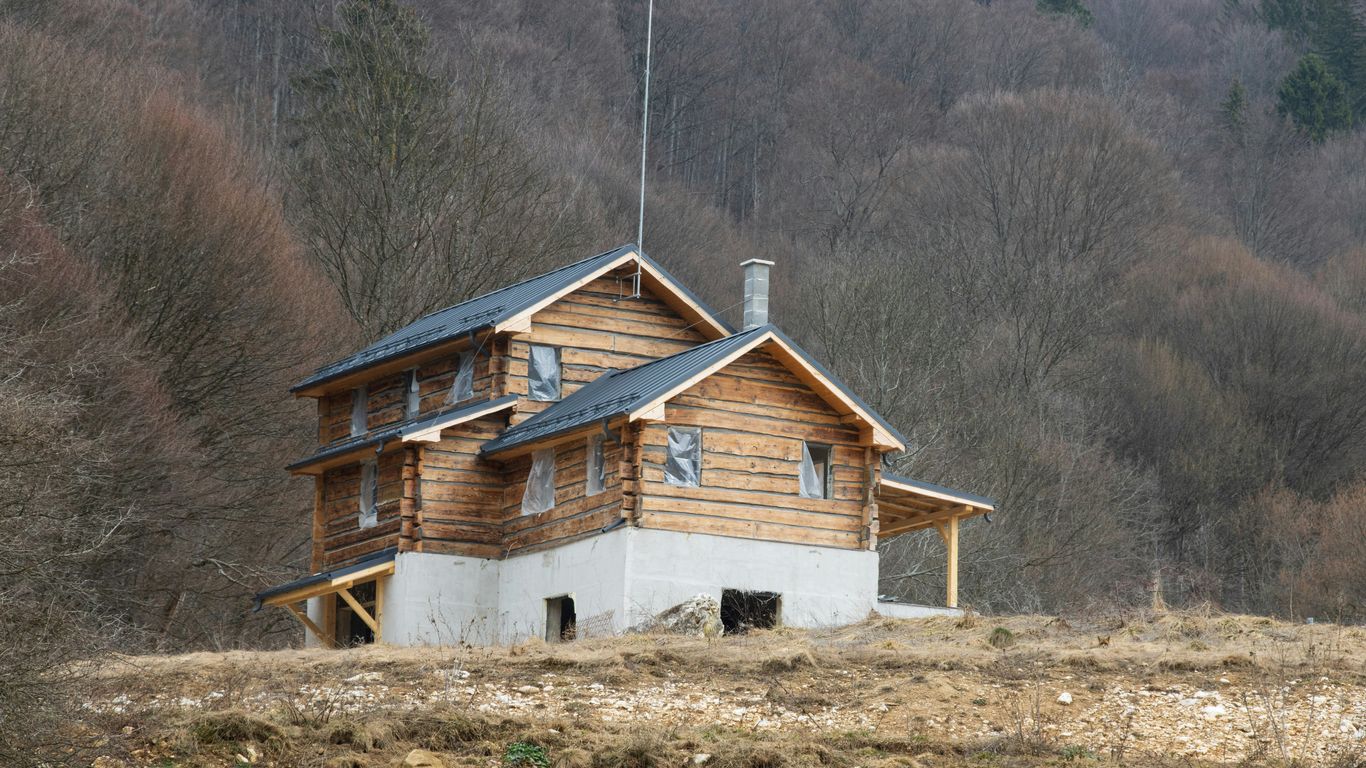 A house in the middle of a field with mountains in the background
