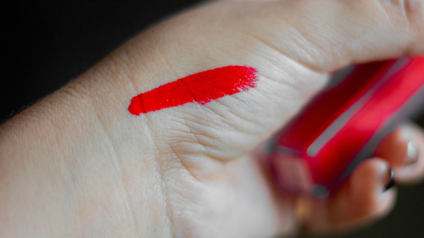 a person holding a cell phone with a red lipstick on it
