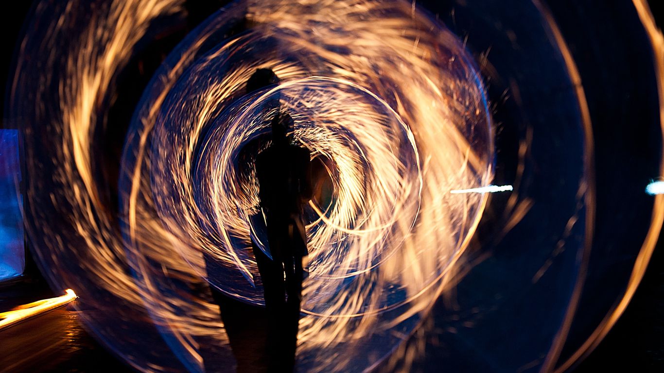 Silhouette with swirling fire trails creating a dramatic light effect.