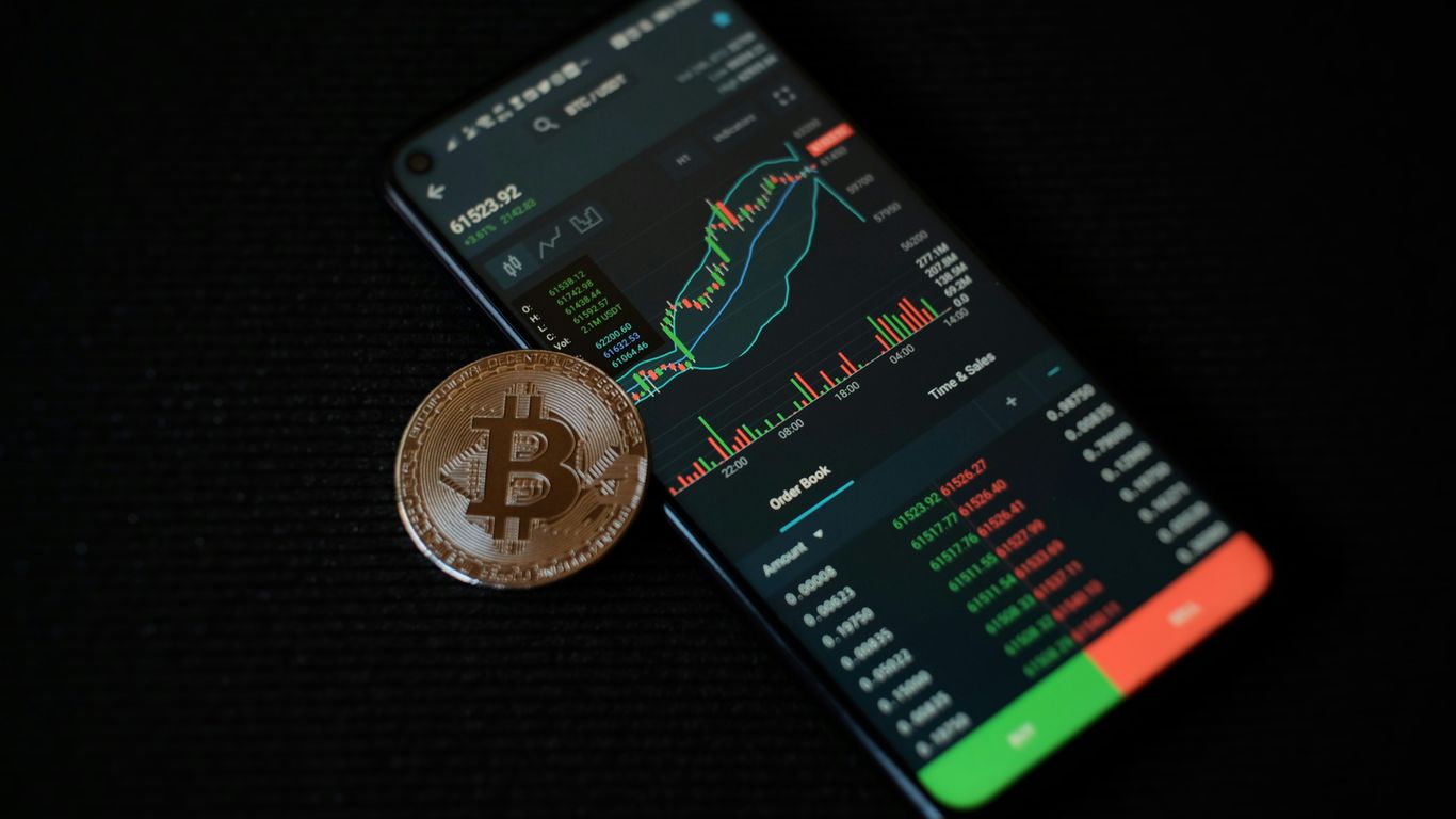 a bitcoin sitting on top of a smart phone