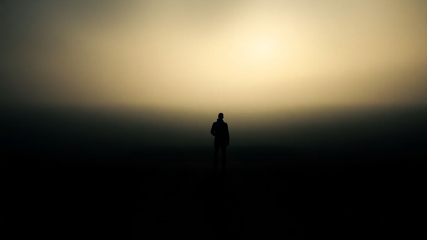 Person at a crossroads, looking towards an uncertain future.