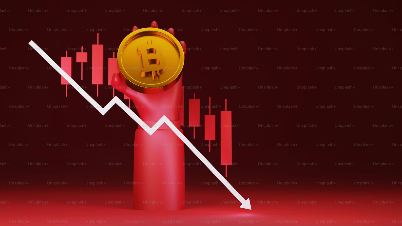 Hand holding a Bitcoin symbol with a downward trend line.