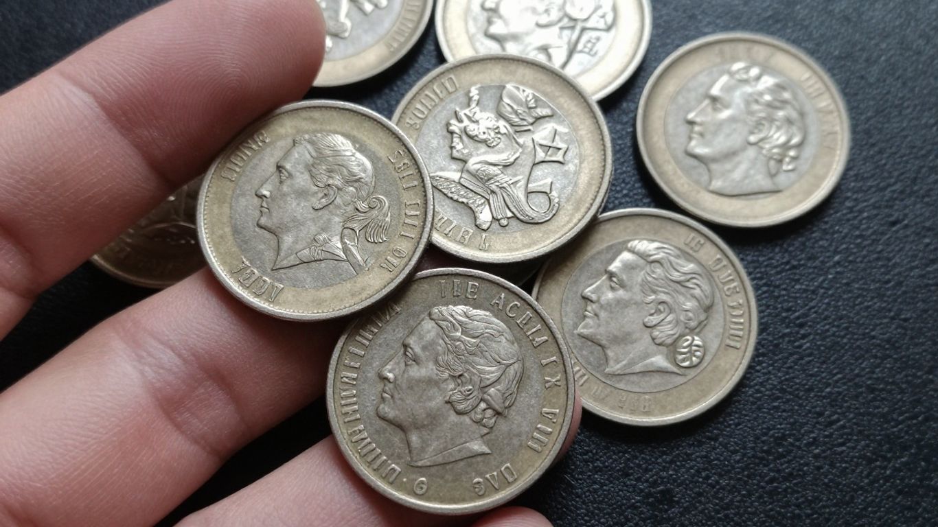 Silver coins scattered on a dark surface.