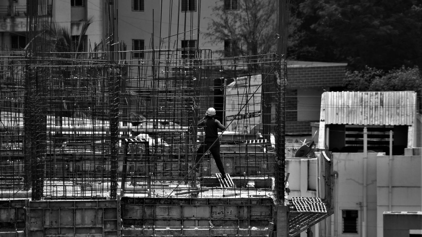 grayscale photo of man in black jacket and pants standing on building