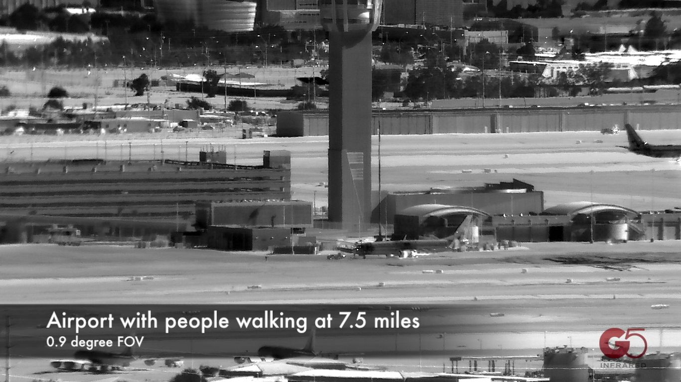 Infrared view of an airport with a control tower and airplanes.