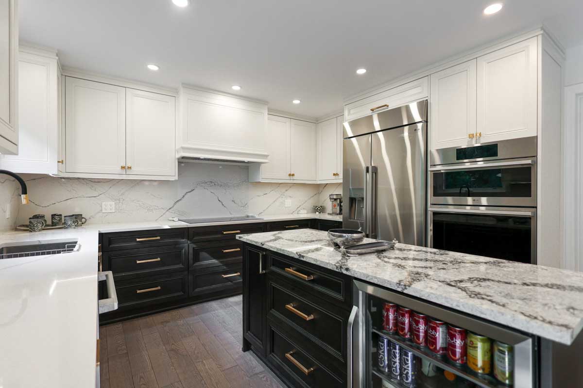 Modern kitchen with white and black cabinets, granite island, and stainless steel appliances.