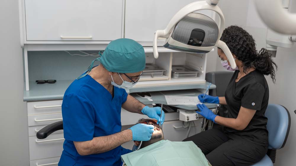 Dr. Reza and his assistant working on a patient in a dental office.