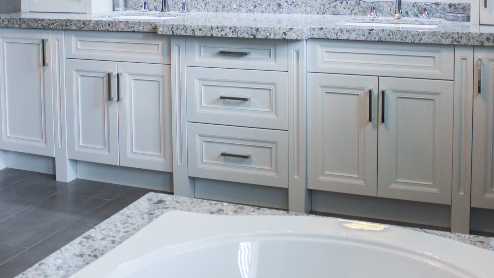 White shaker cabinets with dark hardware and granite countertops.