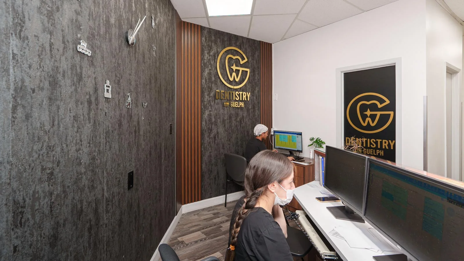 Dentistry on Guelph office reception with staff at computers and logo on wall.