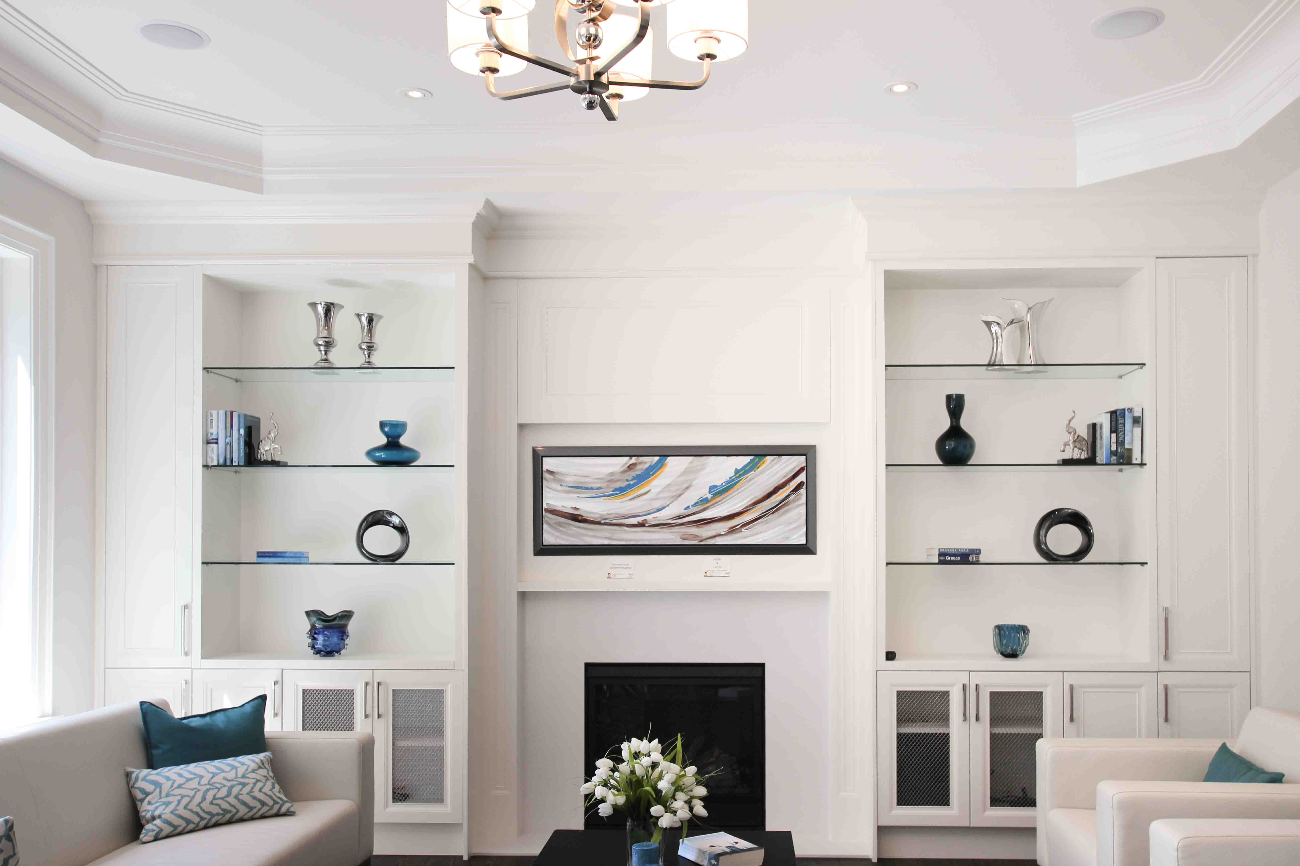 Modern living room with white built-in shelves, fireplace, and abstract art.