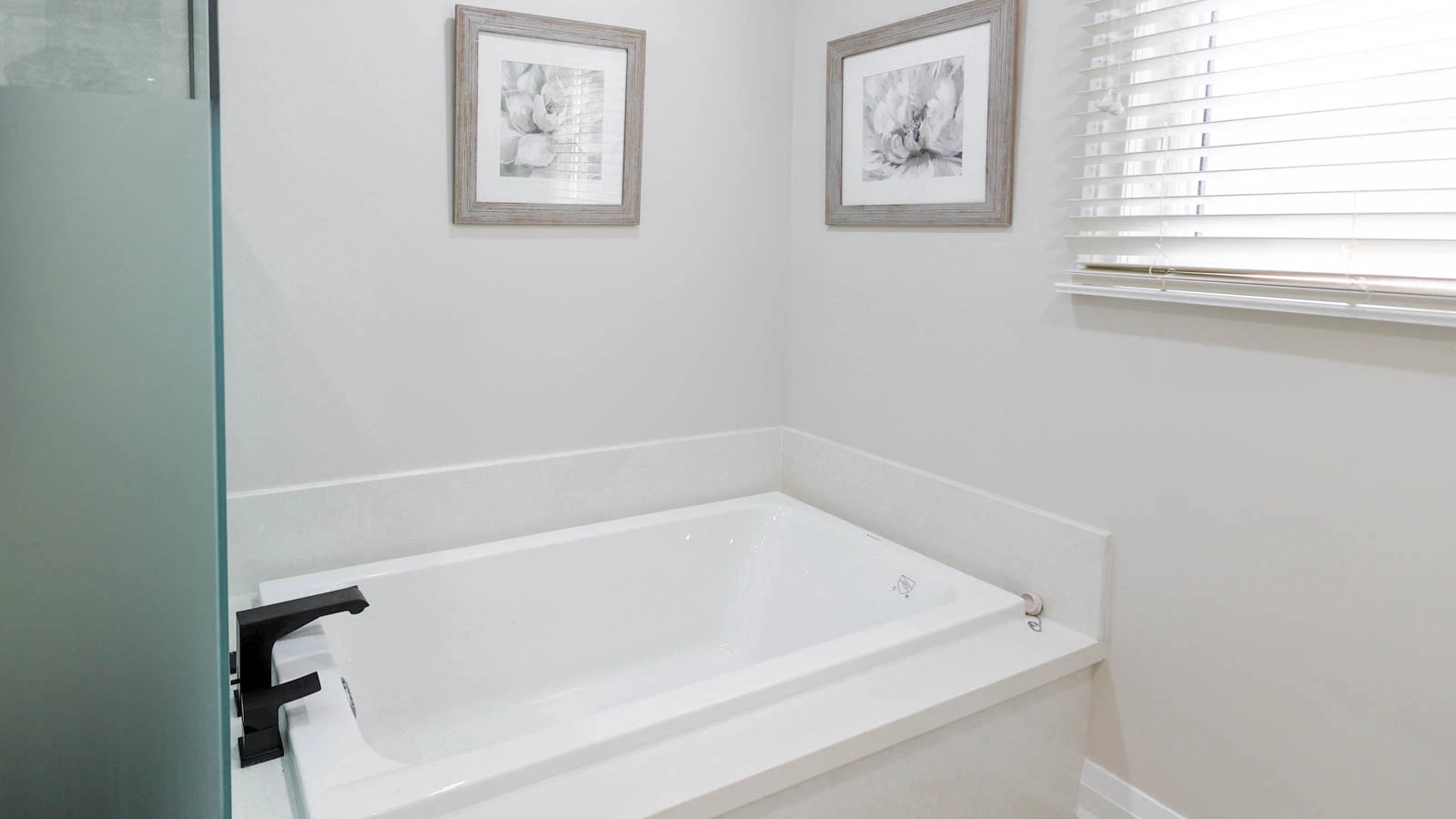 A modern bathroom with a white soaking tub and black faucet.