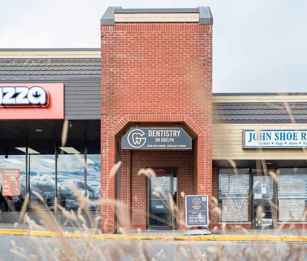 A storefront with "Dentistry on Guelph" and "John Shoe Repair" signs.