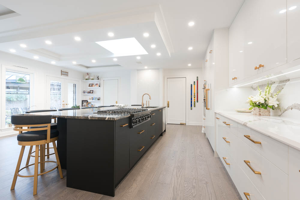 Modern black and white kitchen with a large island and gold accents.