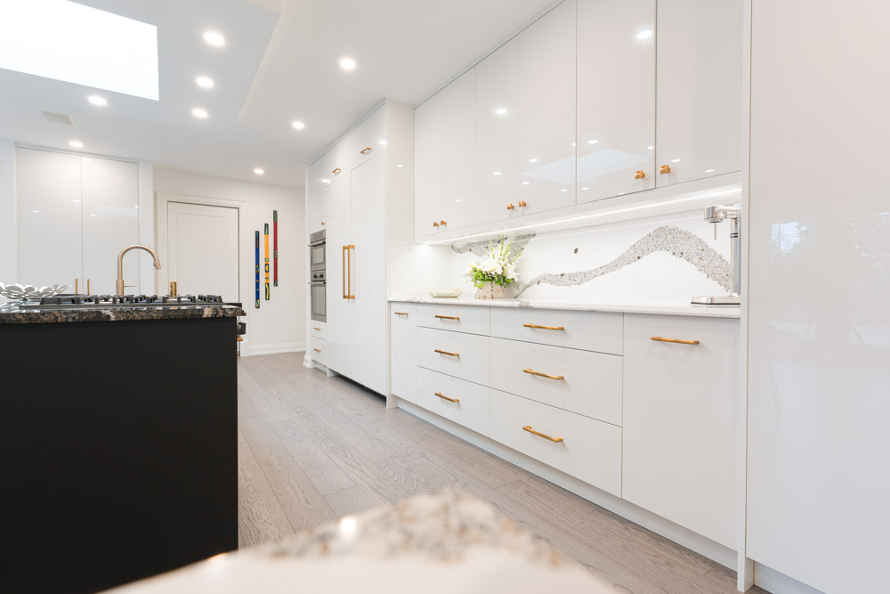 Modern white kitchen with a black island and granite countertop.