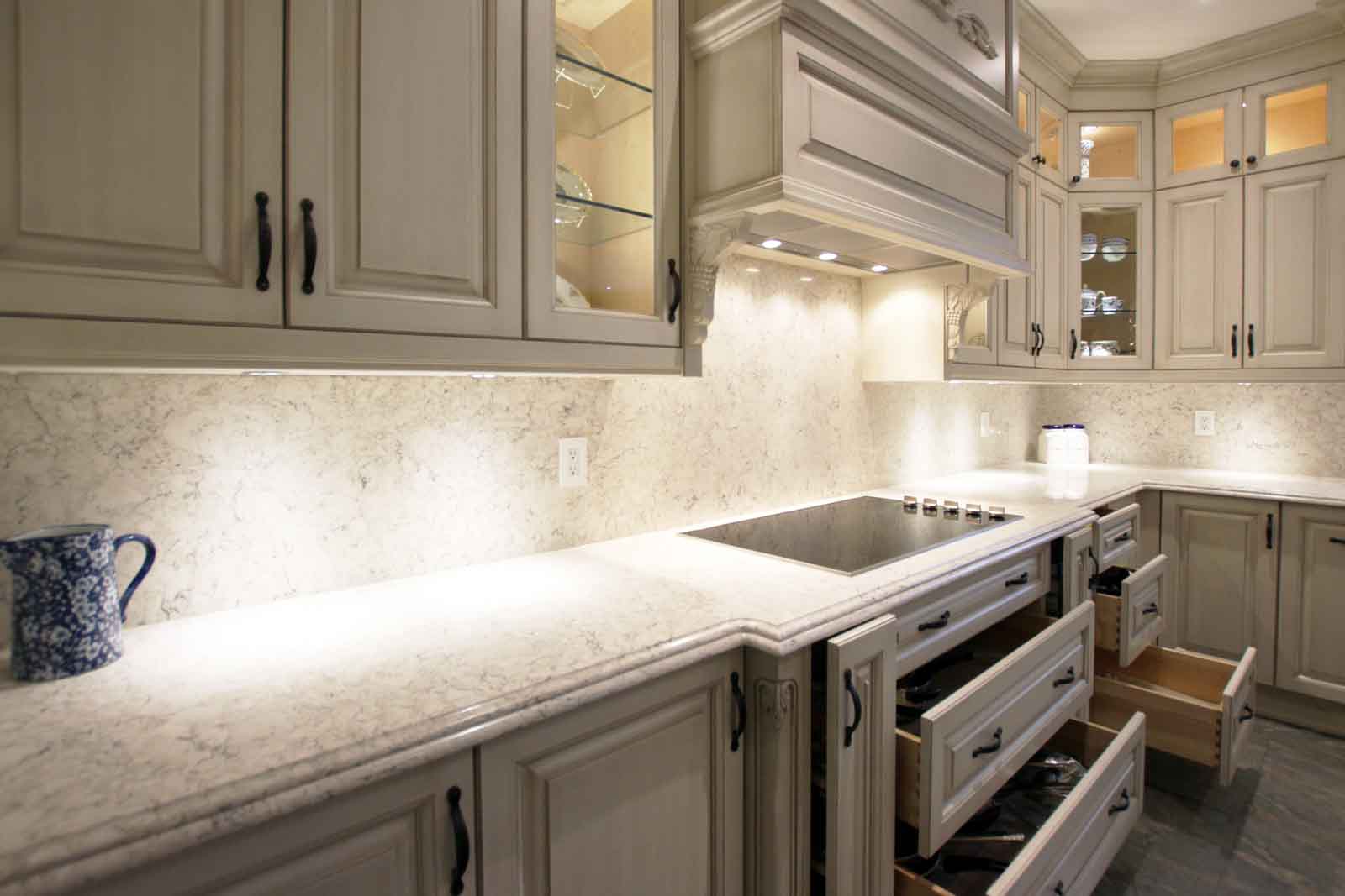 A modern kitchen with cream cabinets, granite countertops, and a black stovetop.