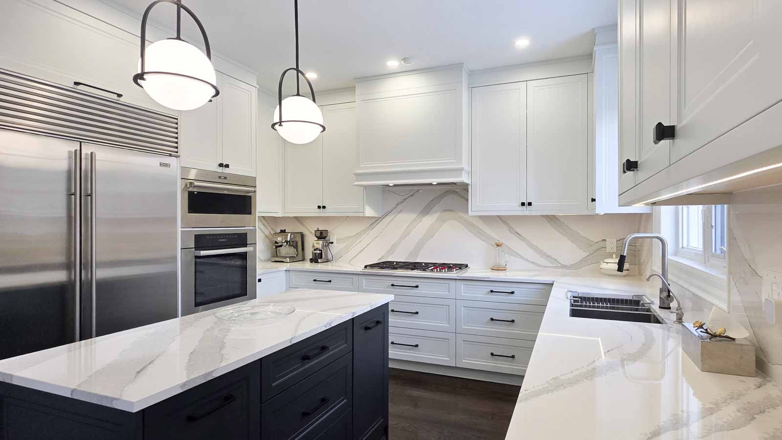 Modern kitchen with white cabinets, marble countertops, and stainless steel appliances.
