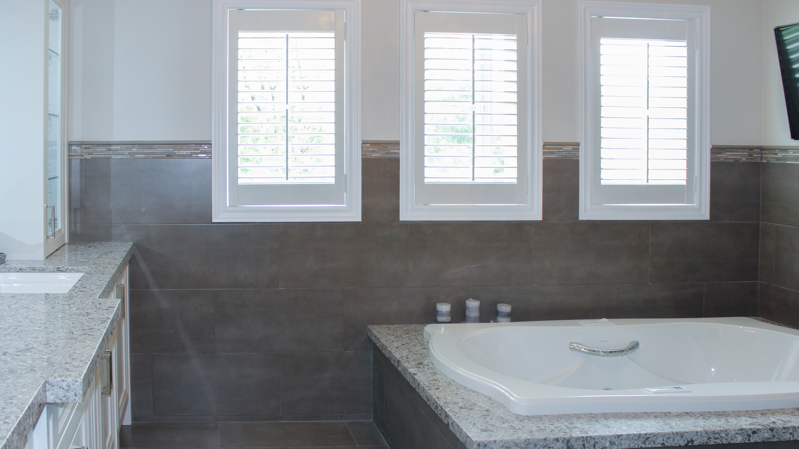 Modern bathroom with a large white bathtub and three windows.