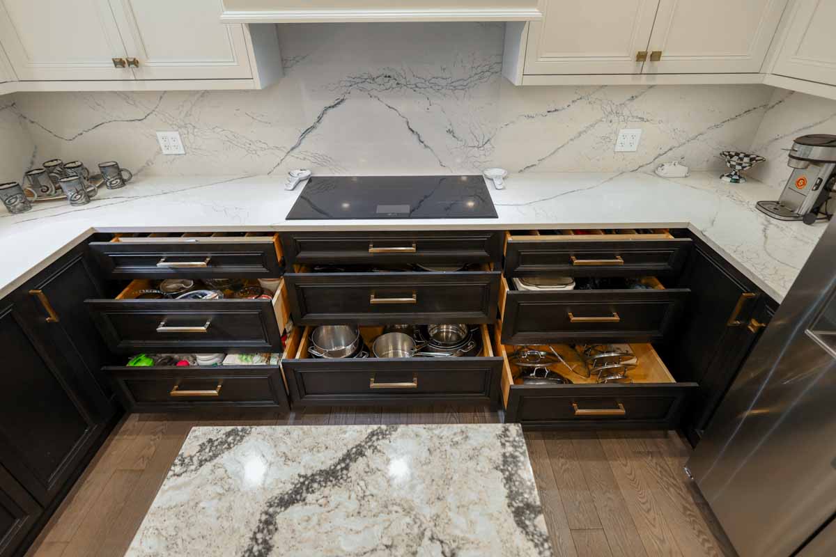 Kitchen drawers are open, revealing pots, pans, and kitchenware.