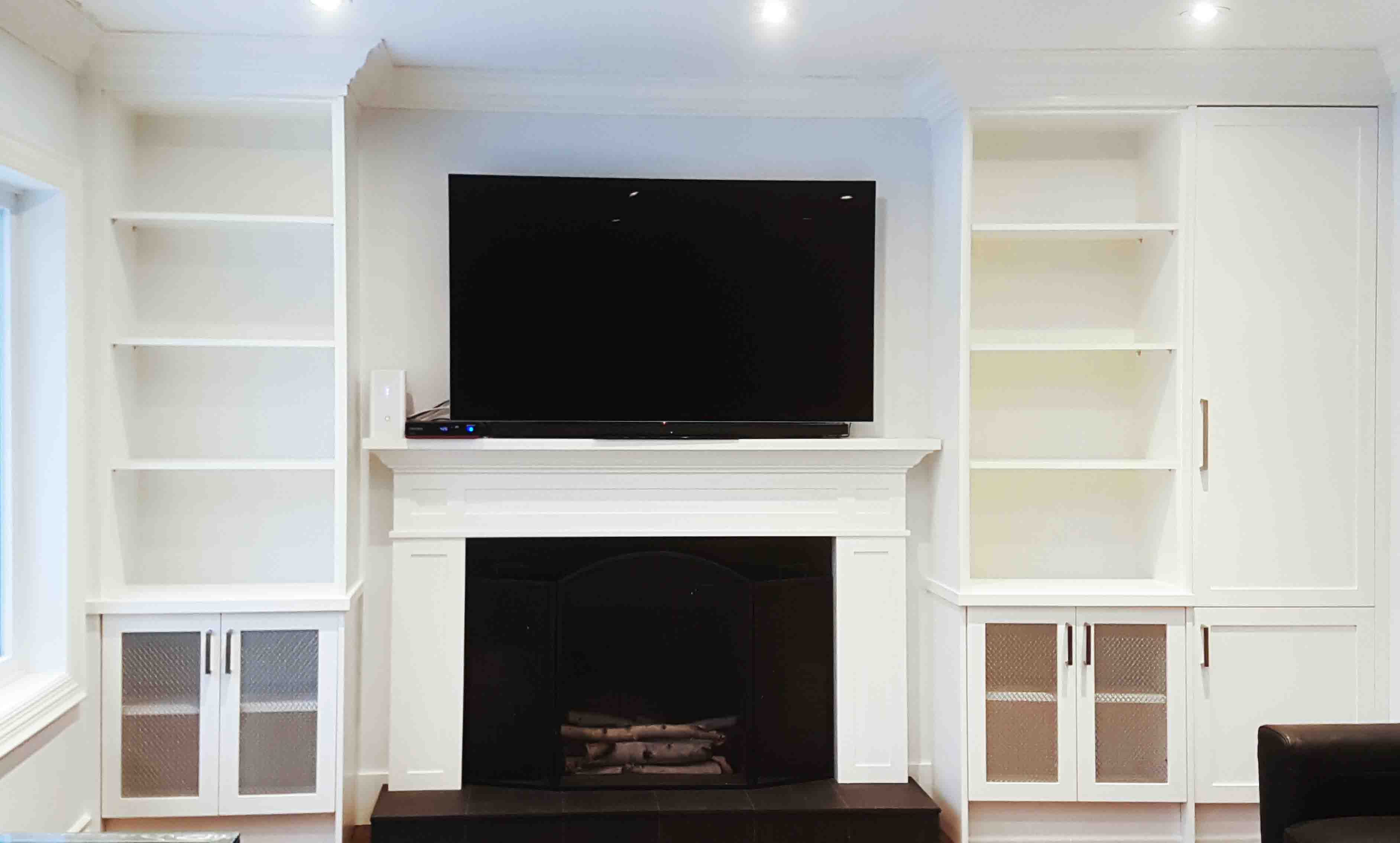 Built-in white bookshelves flank a fireplace with a television above.