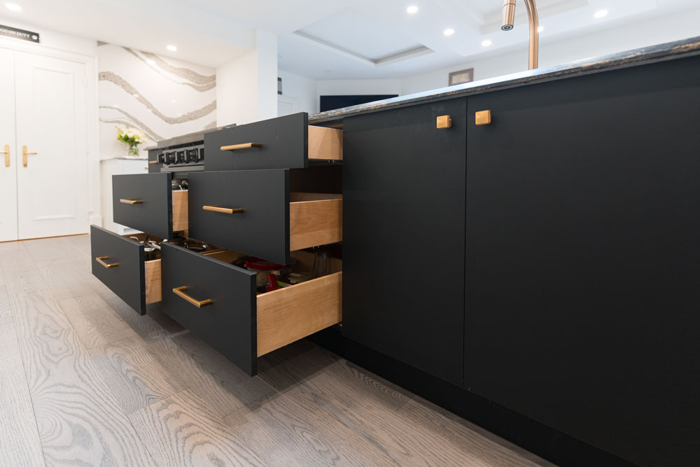 Modern kitchen island with dark gray drawers, some open, revealing wooden interiors.