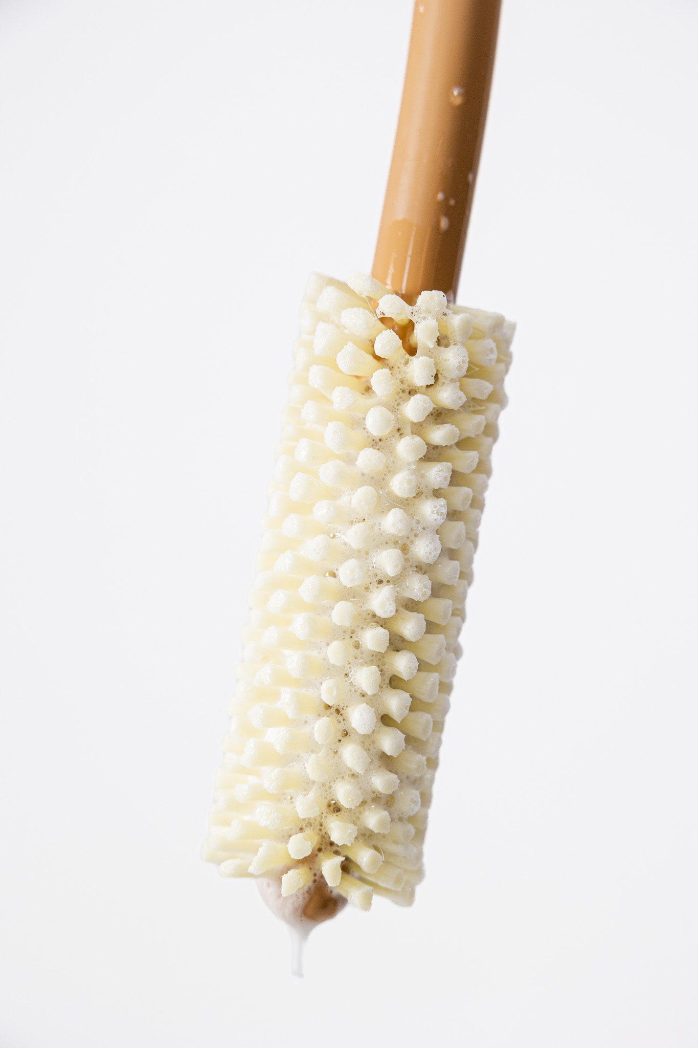 Close-up of soapy bristles on a tan Booty Brush