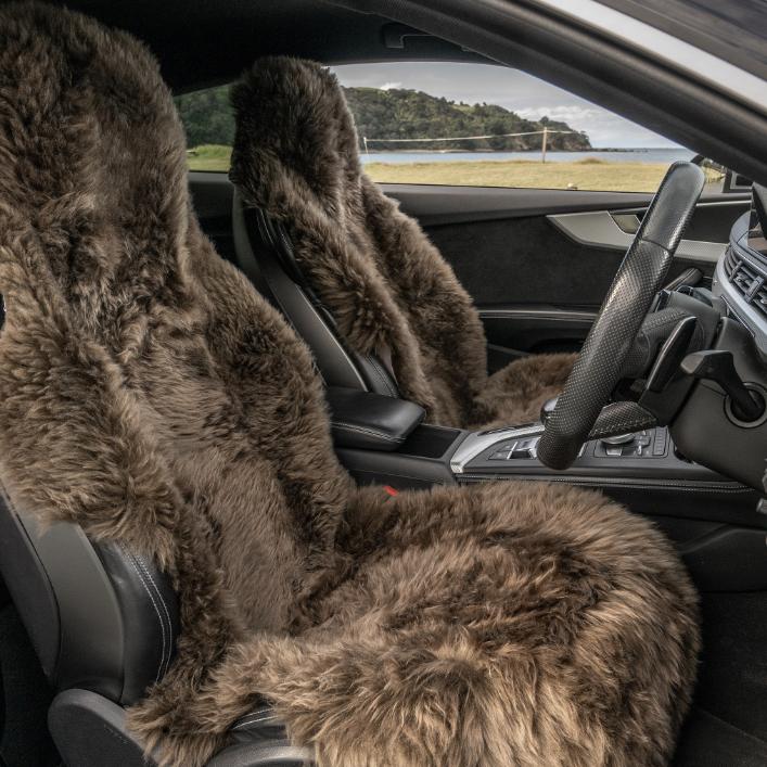 Two long wool chocolate sheepskin car seat covers installed in a luxury car interior