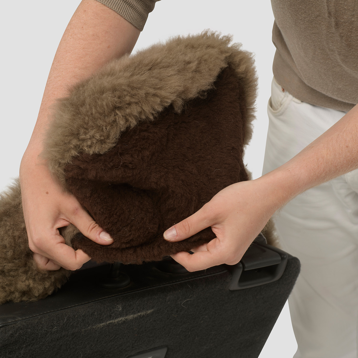 Close-up view of a sheepskin car seat cover fitted securely over a vehicle headrest