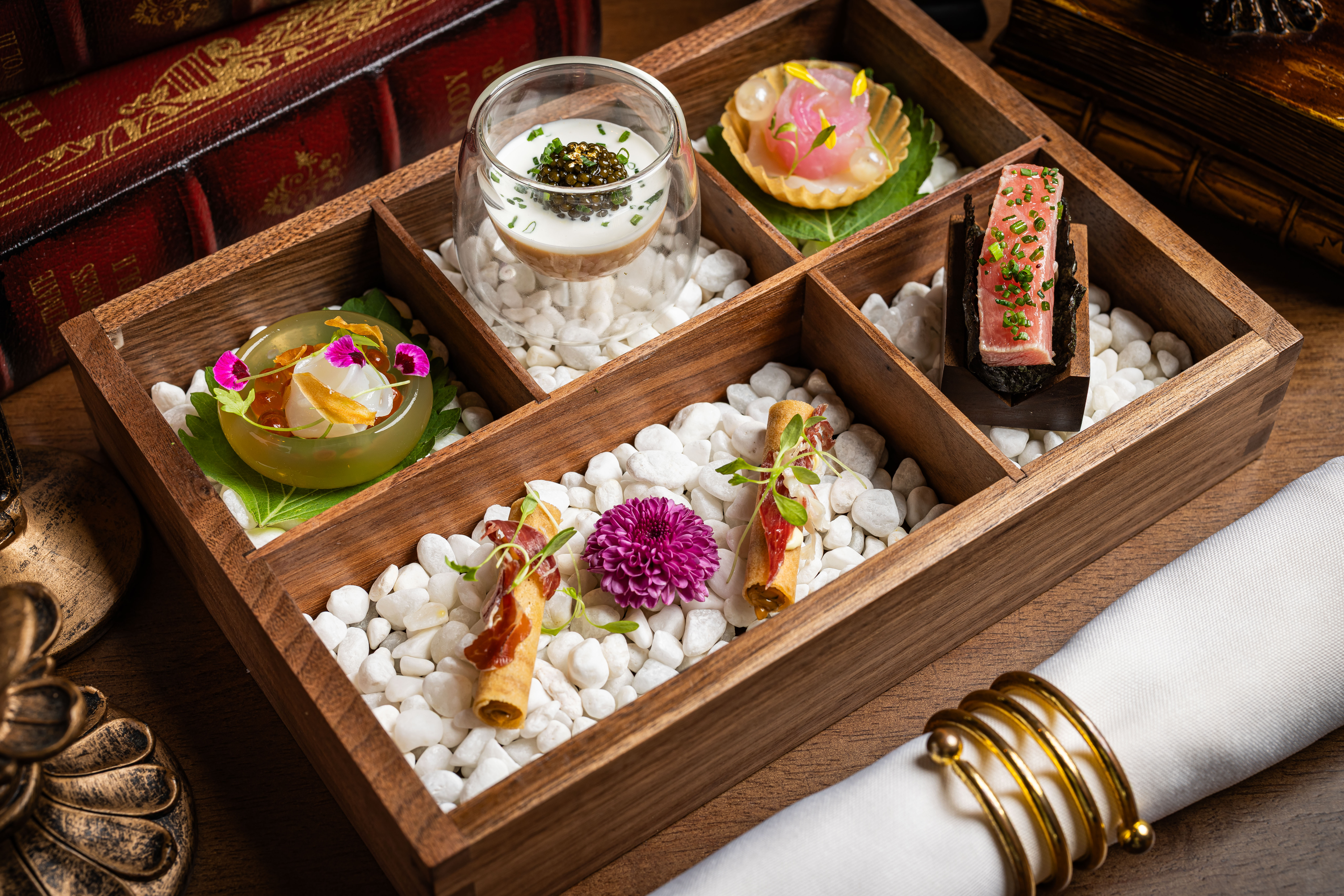 A sophisticated dining table set for a formal tasting dinner at Bochord, featuring elegant plating against a backdrop of warm walnut library-style interiors and Victoria Harbour views.