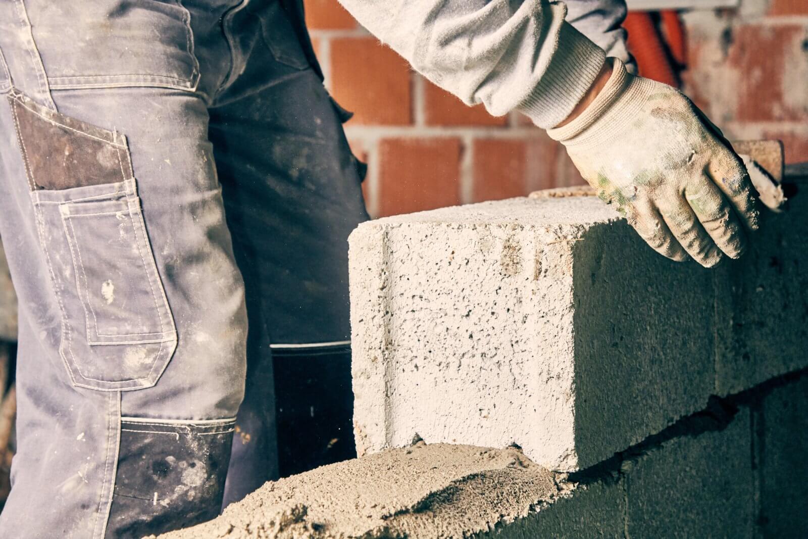 A person is laying a concrete block on a wall
